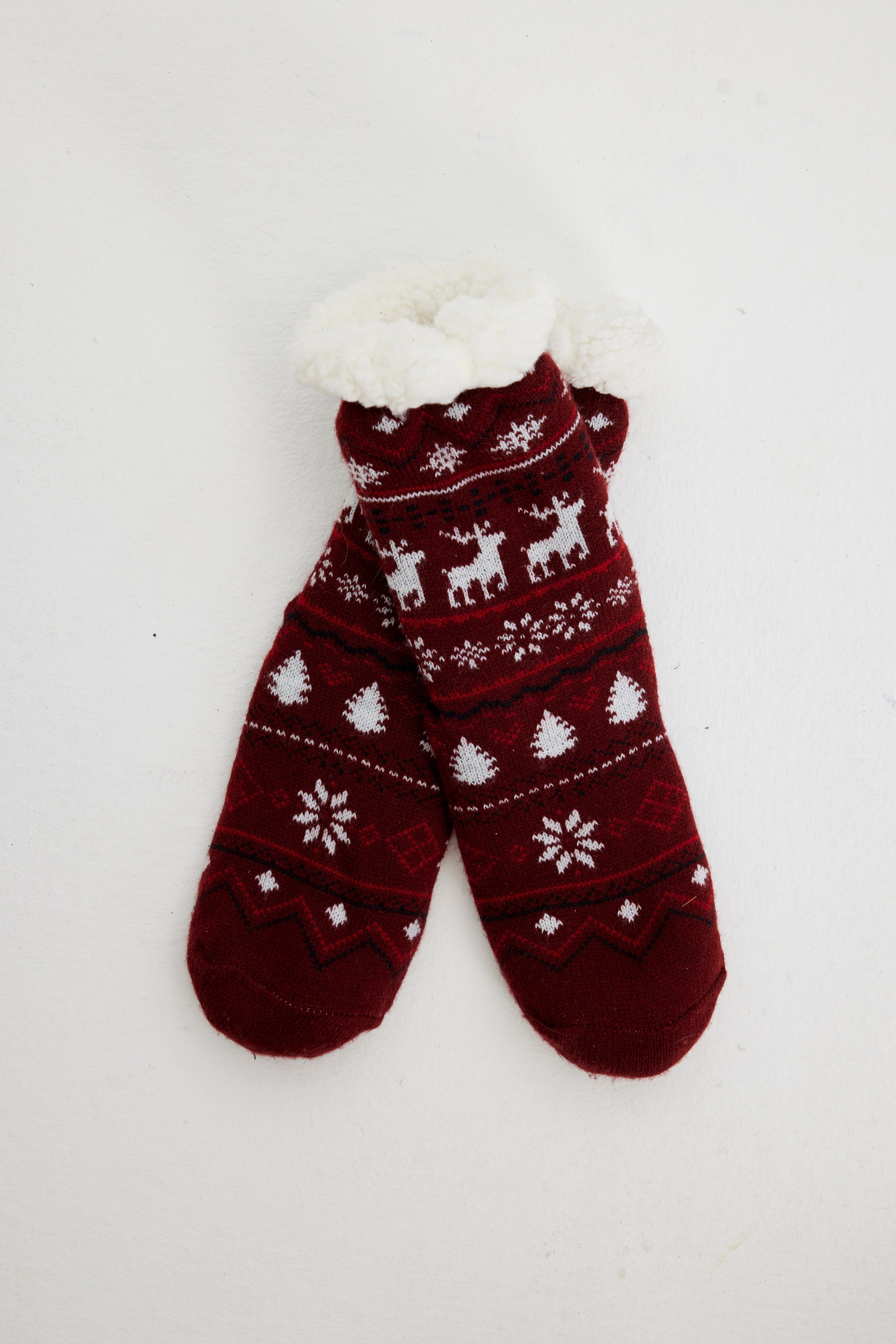 Une paire de chaussettes de Noël rouge foncé ornées de rennes et de cœurs.